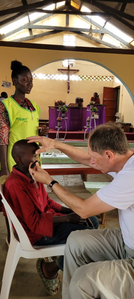 a man holding a child's forehead testing the childs' eyes